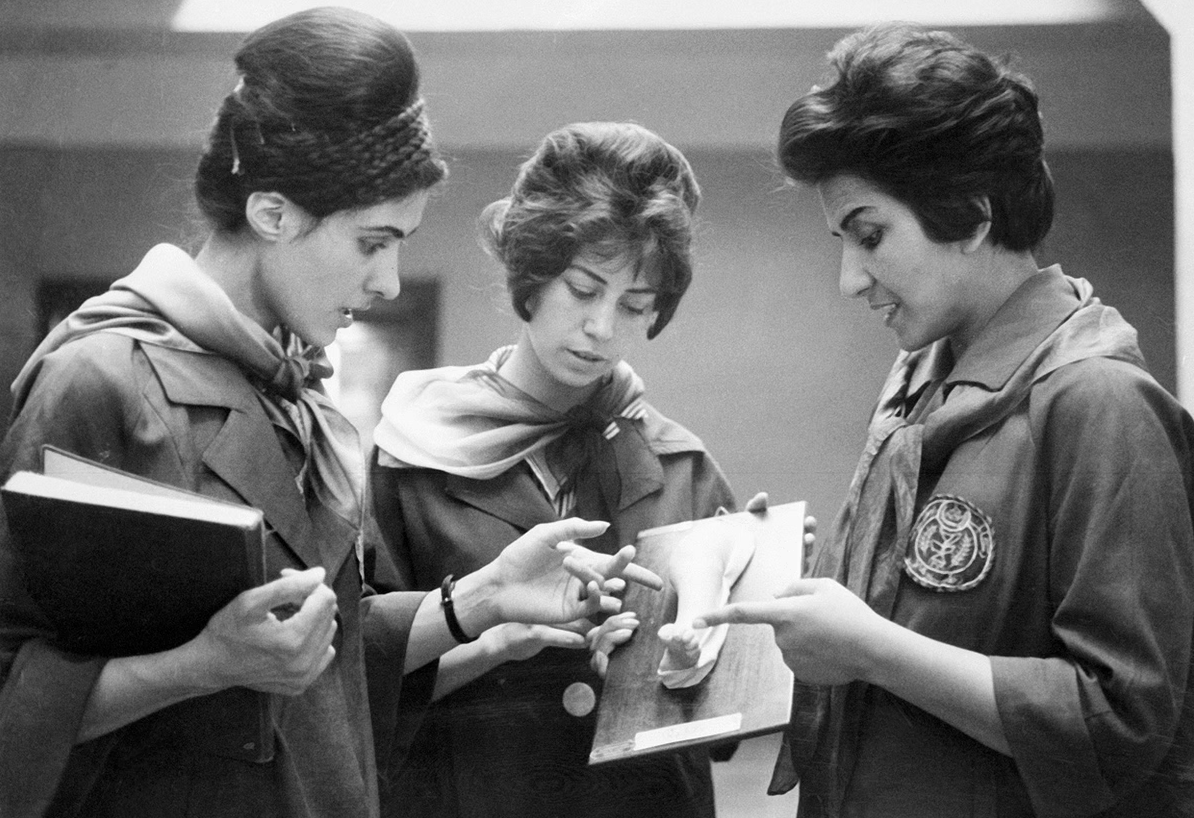 Afghan female medical students examining a plaque.