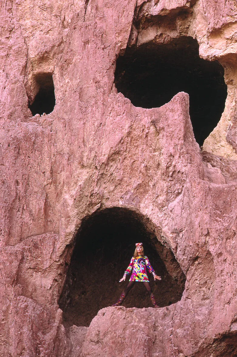 Vogue model in geometric dress inside a rock cave.